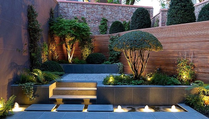 Jardin contemporain aménagé : palissade bois, massifs éclairés et bassin